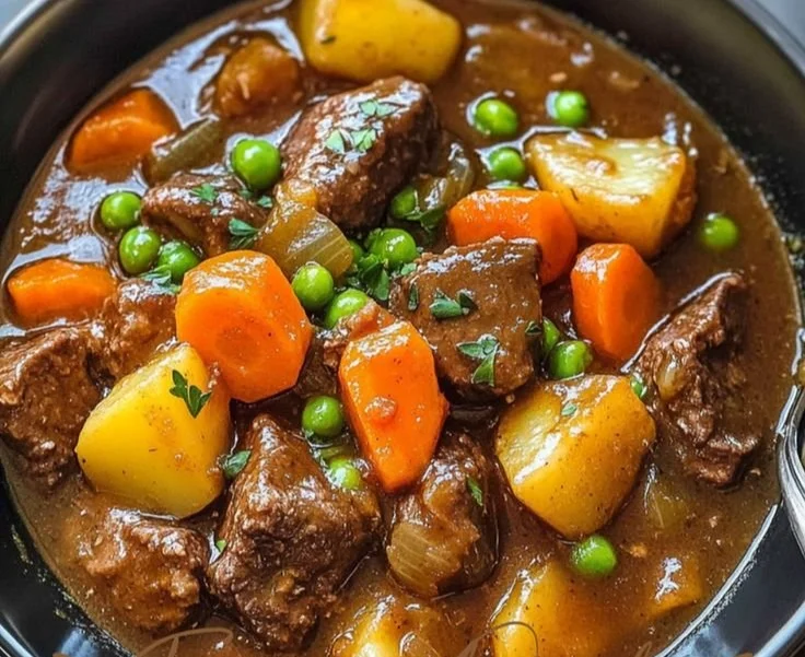 Delicious crockpot beef stew in a bowl with fresh herbs on top