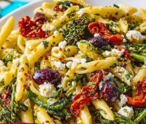 A bowl of delicious Mediterranean Pasta garnished with fresh herbs and vegetables.