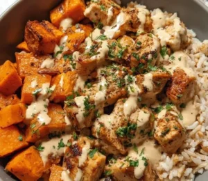Healthy chicken and sweet potato rice bowl topped with fresh vegetables.