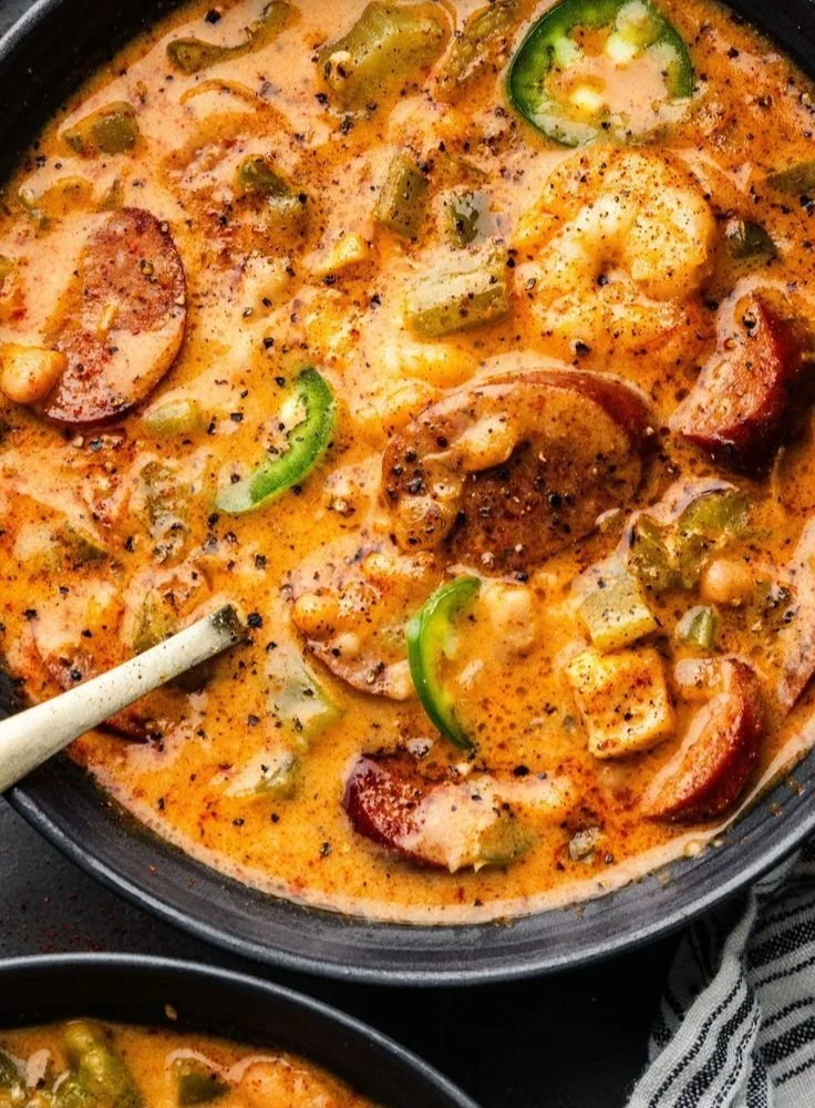 A bowl of creamy Cajun sausage pasta garnished with herbs and spices.
