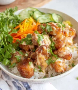 Delicious Bang Bang Chicken Rice Bowl garnished with fresh vegetables