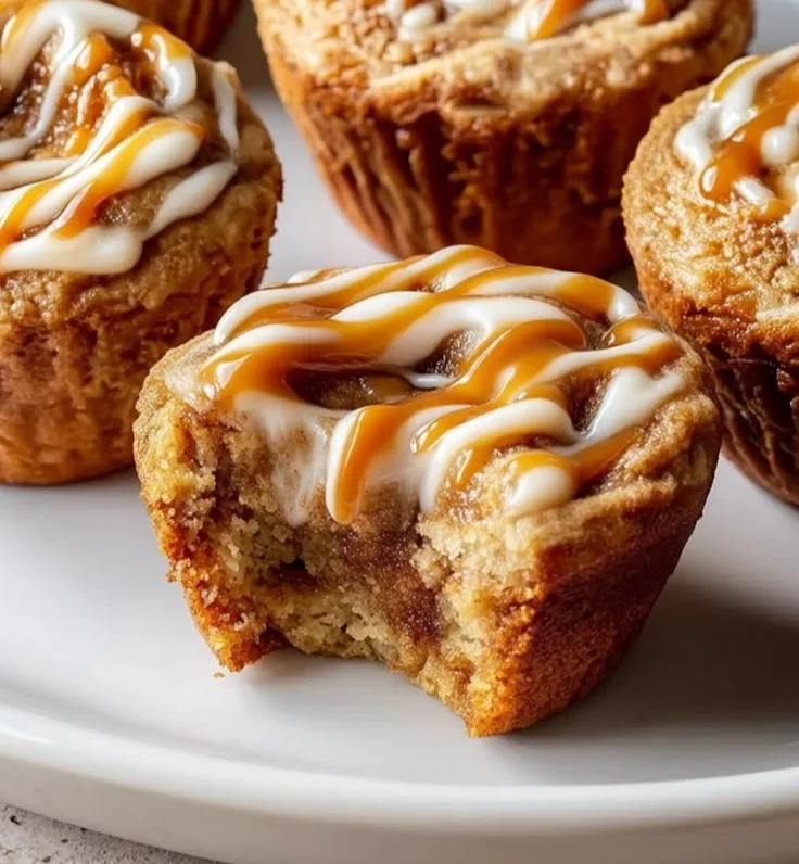 Cinnamon roll protein muffins served on a plate with a cinnamon sprinkle on top.