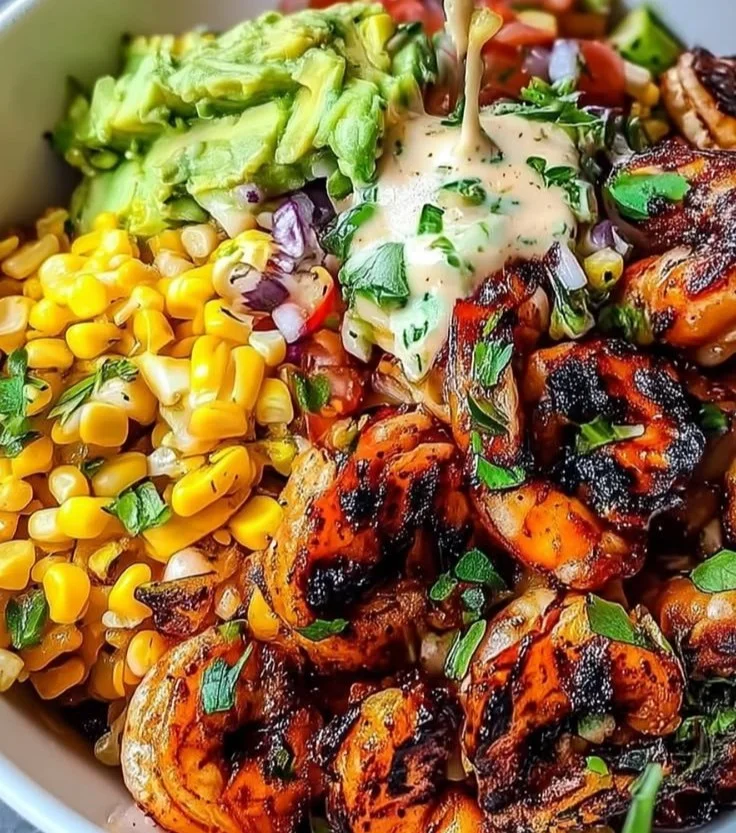 A delicious grilled shrimp bowl topped with fresh vegetables and a zesty sauce