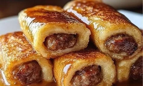 Sausage French Toast Roll-ups with syrup and berries on a plate