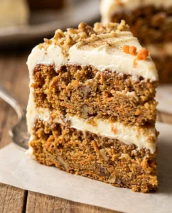 Delicious cream cheese frosted carrot cake slice topped with nuts and carrots